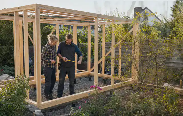 Person plant den Bau eines Gartenhauses auf einer vorbereiteten Fläche; Thema Geräteschuppen, Schwerpunkt Fundament; Ausgangslage.