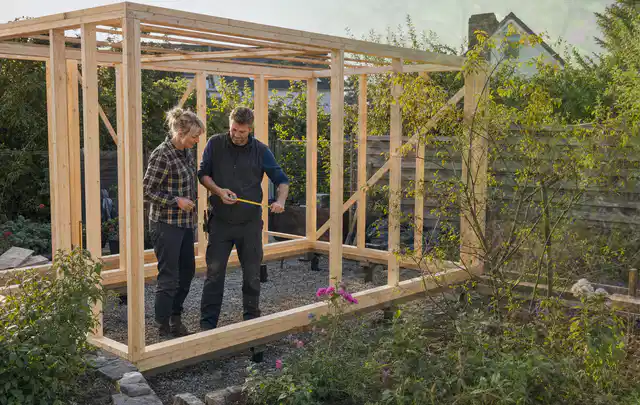 Person plant den Bau eines Gartenhauses auf einer vorbereiteten Fläche; Thema Geräteschuppen, Schwerpunkt Kosten; Kontrolle.