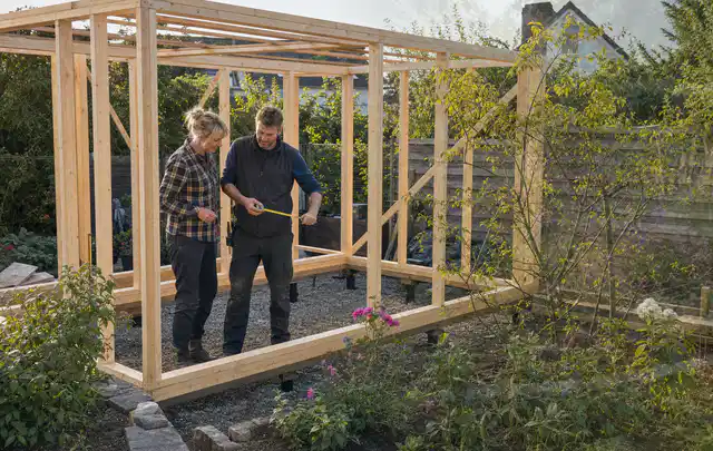 Person plant den Bau eines Gartenhauses auf einer vorbereiteten Fläche; Thema Geräteschuppen, Schwerpunkt Nachhaltigkeit; Ausgangslage.