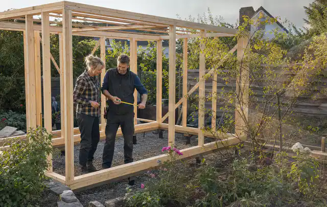 Person plant den Bau eines Gartenhauses auf einer vorbereiteten Fläche; Thema Geräteschuppen, Schwerpunkt Winterschutz; Ausgangslage.