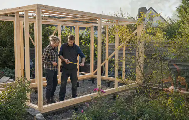 Person plant den Bau eines Gartenhauses auf einer vorbereiteten Fläche; Thema Gewächshäuser, Schwerpunkt Gartenhäuser Bauen; Ergebnis.