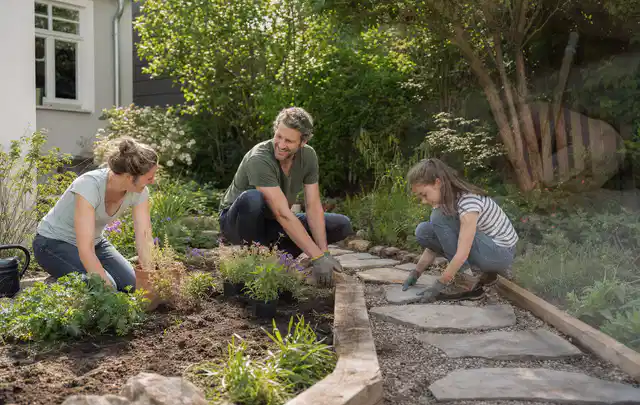 Familie geht auf einem Weg durch einen abwechslungsreich gestalteten Garten; Thema Hanggarten, Schwerpunkt Gärten mit kleiner Fläche; Kontrolle.