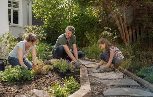 Familie geht auf einem Weg durch einen abwechslungsreich gestalteten Garten; Thema Hanggarten, Schwerpunkt Inspiration; Praxisalltag.