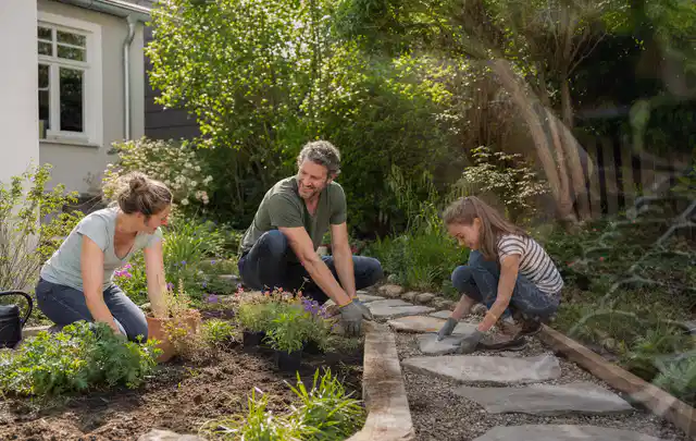 Familie geht auf einem Weg durch einen abwechslungsreich gestalteten Garten; Thema Hanggarten, Schwerpunkt Materialwahl; Praxisalltag.