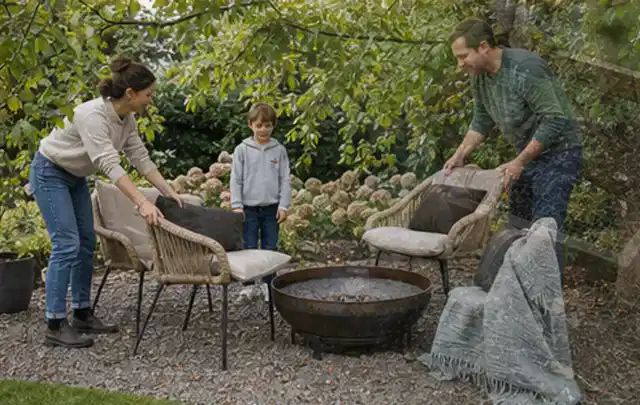 Familie stellt wetterfeste Sessel an einem geschützten Sitzplatz im Garten auf; Thema Hanggarten, Schwerpunkt Naturgarten; Kontrolle.