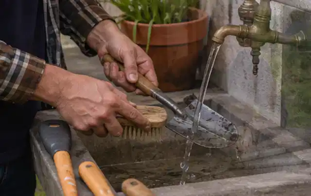 Hände reinigen gebrauchte Gartengeräte mit Bürste und Wasser am Außenbecken; Thema Heckenscheren, Schwerpunkt Checkliste; Ausgangslage.