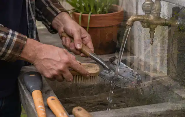 Hände reinigen gebrauchte Gartengeräte mit Bürste und Wasser am Außenbecken; Thema Heckenscheren, Schwerpunkt Kaufberatung; Ausgangslage.