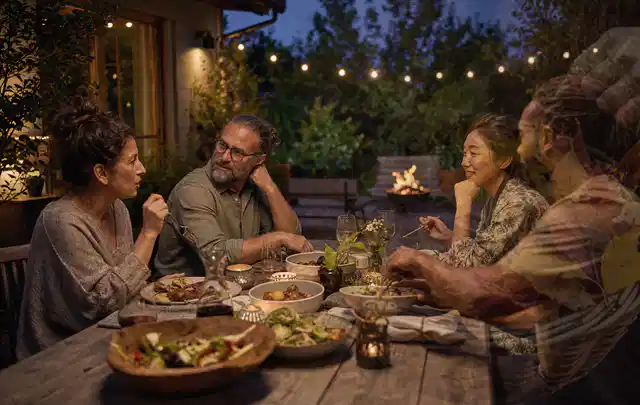 Menschen verbringen einen ruhigen Abend an einem Sitzplatz im Garten; Thema Holzkohlegrills, Schwerpunkt Anwendung; Ausgangslage.