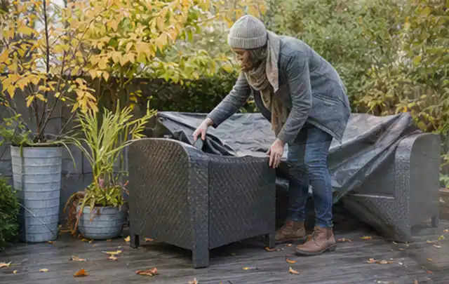 Person deckt Gartenmöbel vor der kalten Jahreszeit sorgfältig ab; Thema Holzkohlegrills, Schwerpunkt Leistung; Ergebnis.