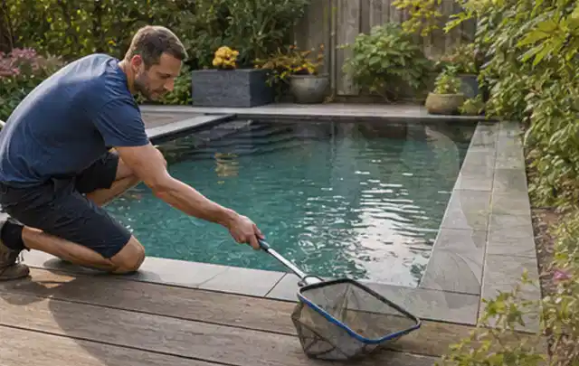 Person entfernt Blätter mit einem Kescher aus einem kleinen Gartenpool; Thema Holzkohlegrills, Schwerpunkt Nachhaltigkeit; Kontrolle.