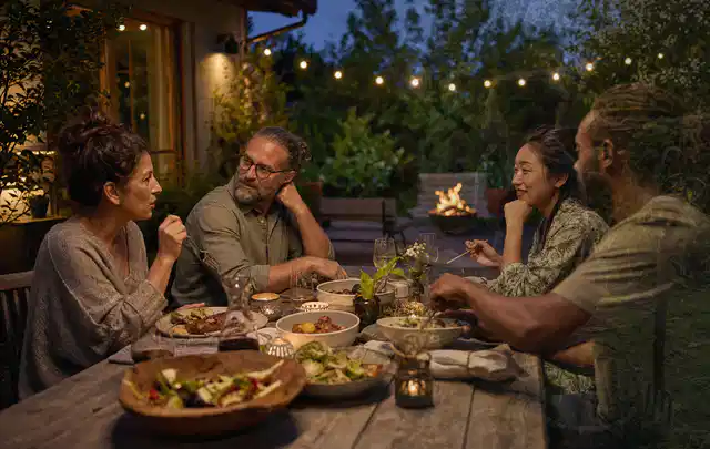 Menschen verbringen einen ruhigen Abend an einem Sitzplatz im Garten; Thema Holzkohlegrills, Schwerpunkt Outdoor Freizeit; Umsetzung.