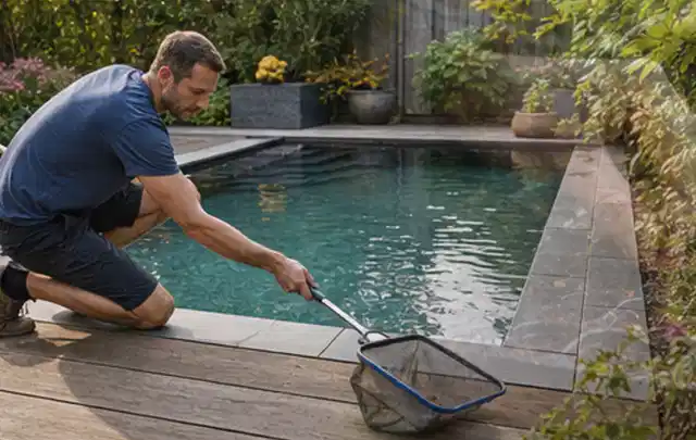 Person entfernt Blätter mit einem Kescher aus einem kleinen Gartenpool; Thema Holzkohlegrills, Schwerpunkt Reinigung; Kontrolle.