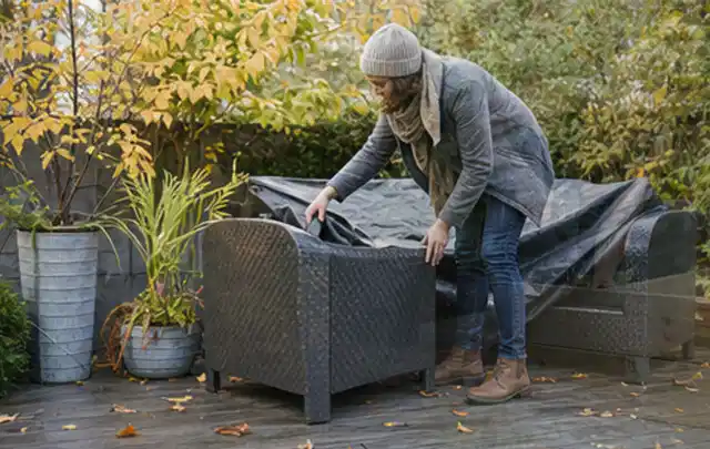 Person deckt Gartenmöbel vor der kalten Jahreszeit sorgfältig ab; Thema Holzkohlegrills, Schwerpunkt Reinigung; Ergebnis.