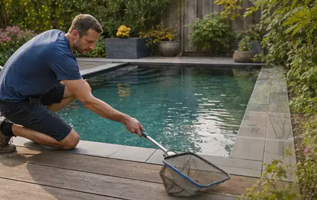 Person entfernt Blätter mit einem Kescher aus einem kleinen Gartenpool; Thema Holzkohlegrills, Schwerpunkt Reparatur; Praxisalltag.