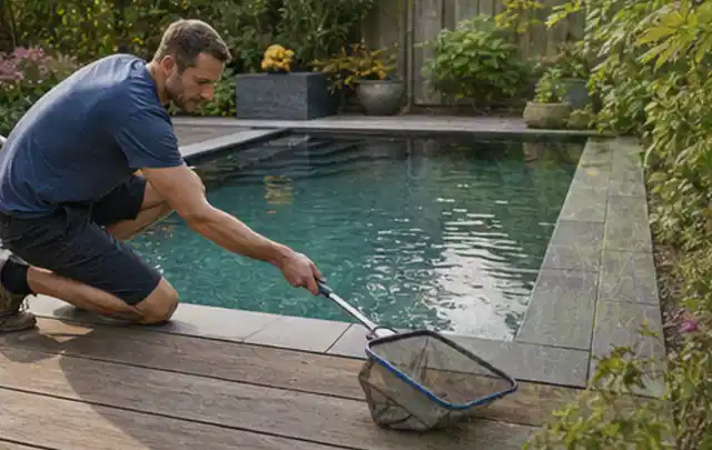 Person entfernt Blätter mit einem Kescher aus einem kleinen Gartenpool; Thema Holzkohlegrills, Schwerpunkt Vergleich; Ergebnis.