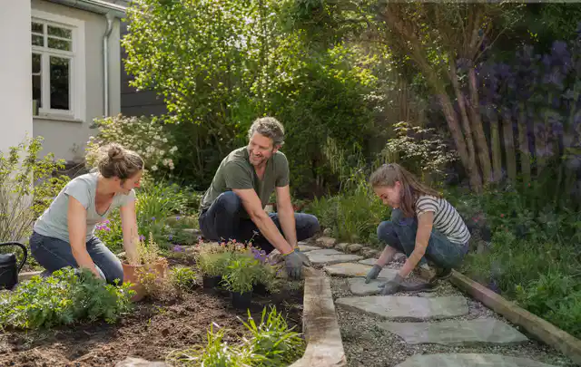 Familie geht auf einem Weg durch einen abwechslungsreich gestalteten Garten; Thema Holzzäune, Schwerpunkt Baurecht; Praxisalltag.