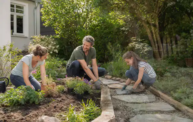 Familie geht auf einem Weg durch einen abwechslungsreich gestalteten Garten; Thema Holzzäune, Schwerpunkt Dimensionierung; Ausgangslage.