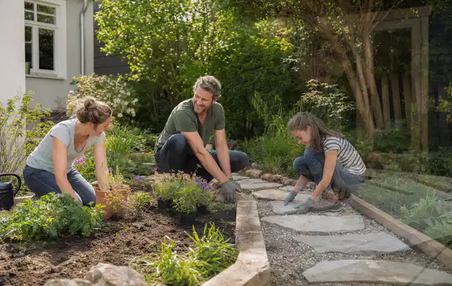 Familie geht auf einem Weg durch einen abwechslungsreich gestalteten Garten; Thema Holzzäune, Schwerpunkt Materialwahl; Praxisalltag.