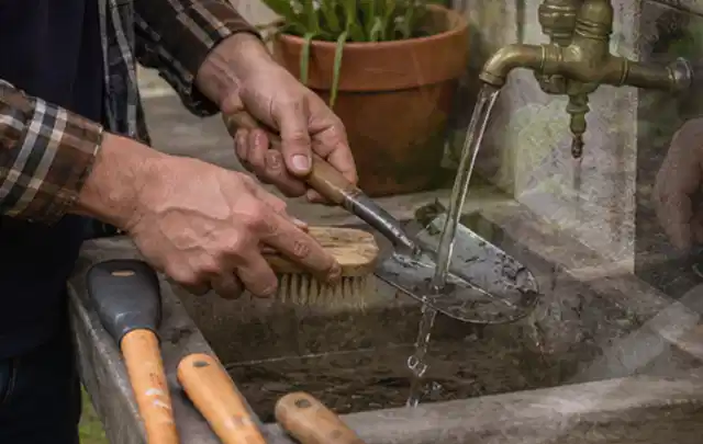 Hände reinigen gebrauchte Gartengeräte mit Bürste und Wasser am Außenbecken; Thema Husqvarna Automower, Schwerpunkt Dimensionierung; Umsetzung.