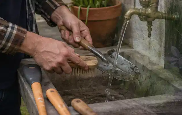 Hände reinigen gebrauchte Gartengeräte mit Bürste und Wasser am Außenbecken; Thema Husqvarna Automower, Schwerpunkt Mähroboter; Umsetzung.