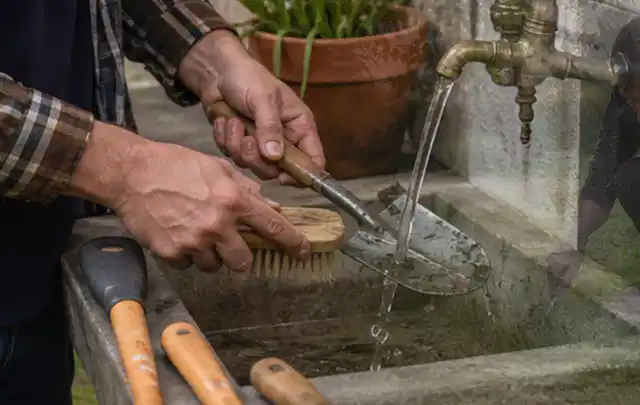 Hände reinigen gebrauchte Gartengeräte mit Bürste und Wasser am Außenbecken; Thema Husqvarna Automower, Schwerpunkt Vergleich; Umsetzung.