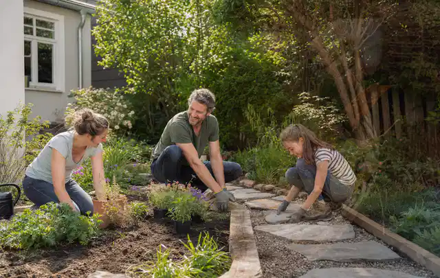 Familie geht auf einem Weg durch einen abwechslungsreich gestalteten Garten; Thema Insektenfreundlicher Garten, Schwerpunkt Materialwahl; Ergebnis.
