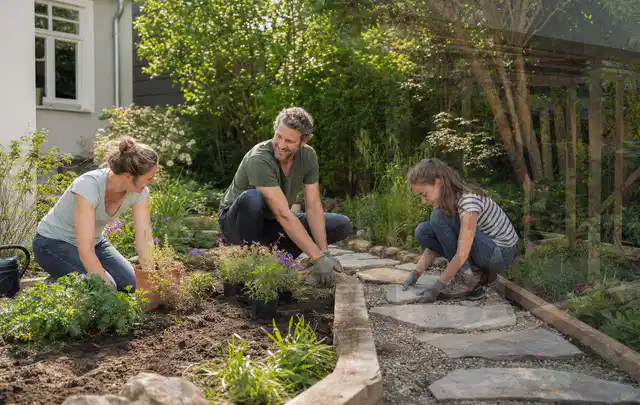 Familie geht auf einem Weg durch einen abwechslungsreich gestalteten Garten; Thema Insektenfreundlicher Garten, Schwerpunkt Praxisbeispiele; Praxisalltag.