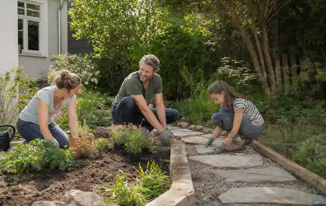 Familie geht auf einem Weg durch einen abwechslungsreich gestalteten Garten; Thema Insektenfreundlicher Garten, Schwerpunkt Privatsphäre; Praxisalltag.