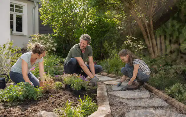 Familie geht auf einem Weg durch einen abwechslungsreich gestalteten Garten; Thema Japanischer Garten, Schwerpunkt Naturgarten; Kontrolle.