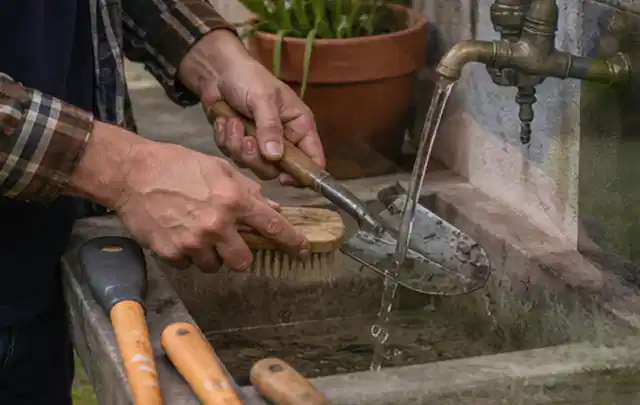 Hände reinigen gebrauchte Gartengeräte mit Bürste und Wasser am Außenbecken; Thema Kaufempfehlung, Schwerpunkt Produktberatung; Kontrolle.