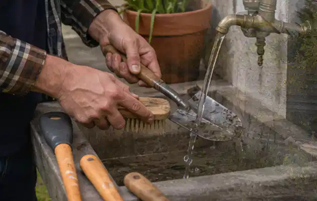 Hände reinigen gebrauchte Gartengeräte mit Bürste und Wasser am Außenbecken; Thema Komposter, Schwerpunkt Kaufberatung; Ergebnis.
