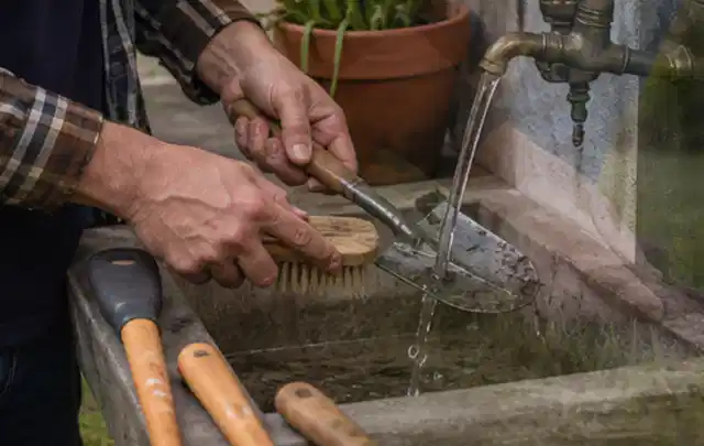 Hände reinigen gebrauchte Gartengeräte mit Bürste und Wasser am Außenbecken; Thema Komposter, Schwerpunkt Reinigung; Ausgangslage.