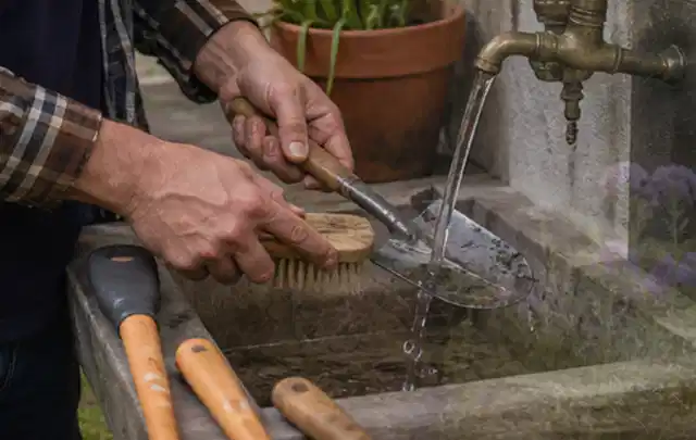 Hände reinigen gebrauchte Gartengeräte mit Bürste und Wasser am Außenbecken; Thema Komposter, Schwerpunkt Systemvergleich; Umsetzung.