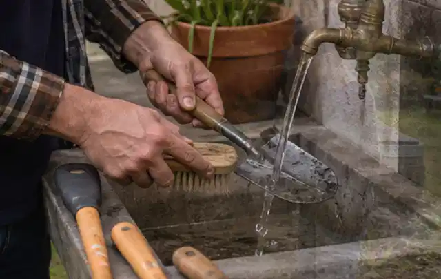 Hände reinigen gebrauchte Gartengeräte mit Bürste und Wasser am Außenbecken; Thema Kress Mission, Schwerpunkt Checkliste; Umsetzung.