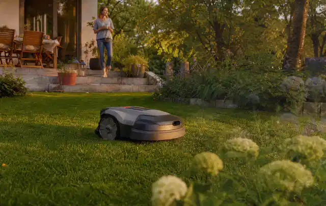 Mähroboter fährt am Abend über einen Rasen im Familiengarten; Thema Kress Mission, Schwerpunkt Dimensionierung; Kontrolle.
