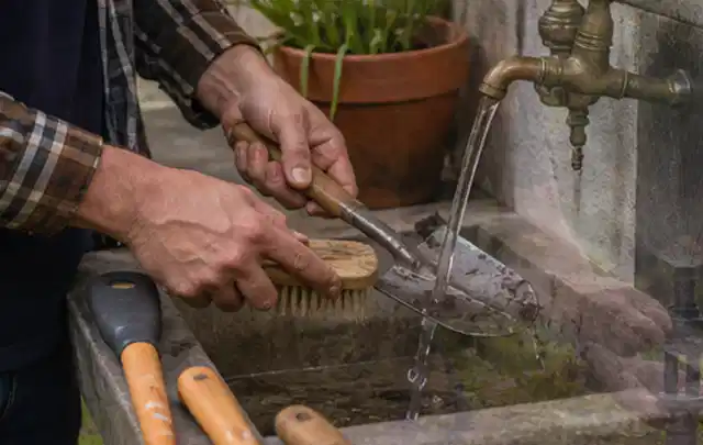 Hände reinigen gebrauchte Gartengeräte mit Bürste und Wasser am Außenbecken; Thema Kress Mission, Schwerpunkt Gärten mit kleiner Fläche; Ausgangslage.
