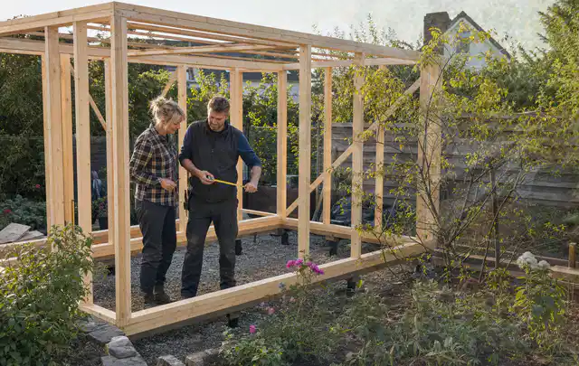 Person plant den Bau eines Gartenhauses auf einer vorbereiteten Fläche; Thema Lagerhaus im Garten, Schwerpunkt Checkliste; Praxisalltag.
