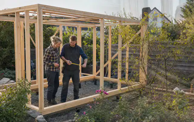 Person plant den Bau eines Gartenhauses auf einer vorbereiteten Fläche; Thema Lagerhaus im Garten, Schwerpunkt Fundament; Ergebnis.