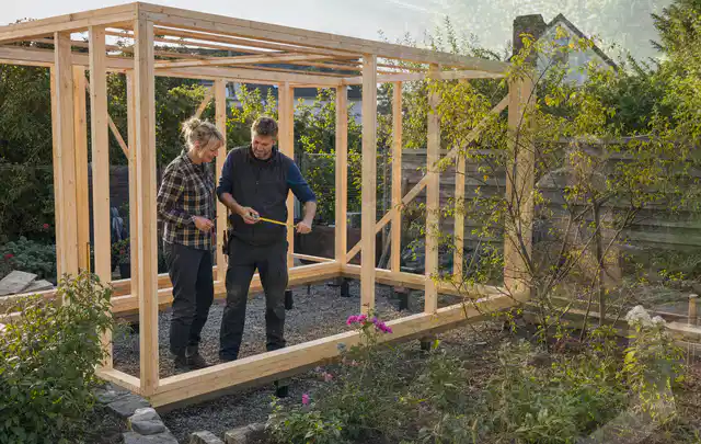 Person plant den Bau eines Gartenhauses auf einer vorbereiteten Fläche; Thema Lagerhaus im Garten, Schwerpunkt Kosten; Kontrolle.