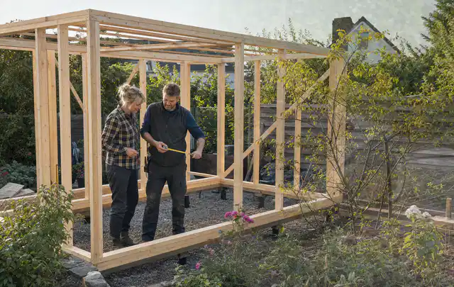 Person plant den Bau eines Gartenhauses auf einer vorbereiteten Fläche; Thema Lagerhaus im Garten, Schwerpunkt Materialwahl; Praxisalltag.