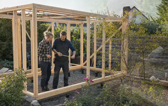 Person plant den Bau eines Gartenhauses auf einer vorbereiteten Fläche; Thema Lagerhaus im Garten, Schwerpunkt Nachhaltigkeit; Praxisalltag.