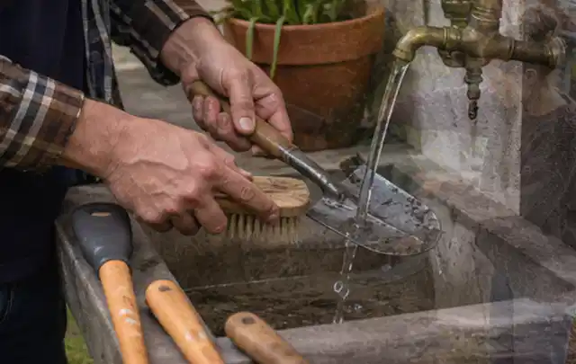 Hände reinigen gebrauchte Gartengeräte mit Bürste und Wasser am Außenbecken; Thema Mähroboter Akkus, Schwerpunkt Bestenliste; Kontrolle.