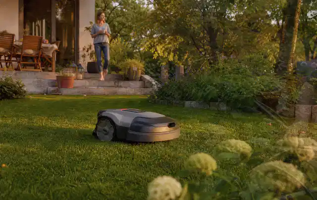 Mähroboter fährt am Abend über einen Rasen im Familiengarten; Thema Mähroboter Akkus, Schwerpunkt Dimensionierung; Kontrolle.