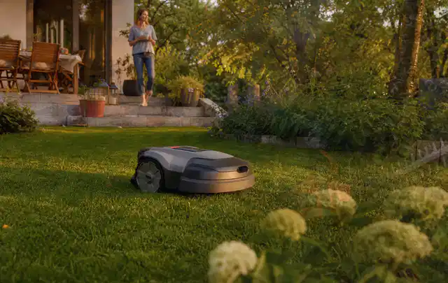 Mähroboter fährt am Abend über einen Rasen im Familiengarten; Thema Mähroboter für kleine Gärten, Schwerpunkt Systemvergleich; Ergebnis.