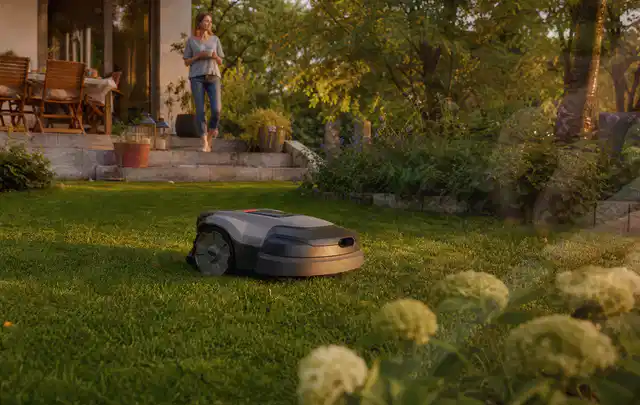 Mähroboter fährt am Abend über einen Rasen im Familiengarten; Thema Mähroboter Garagen, Schwerpunkt Bestenliste; Ausgangslage.