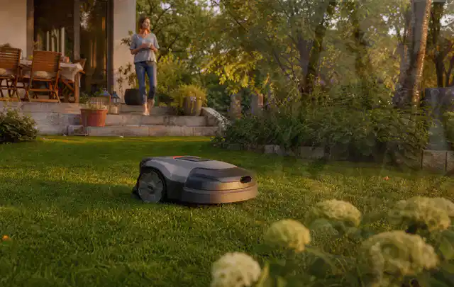 Mähroboter fährt am Abend über einen Rasen im Familiengarten; Thema Mähroboter Garagen, Schwerpunkt Kaufberatung; Kontrolle.