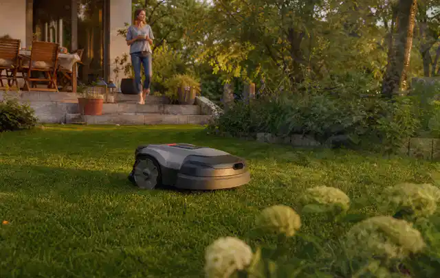 Mähroboter fährt am Abend über einen Rasen im Familiengarten; Thema Mähroboter Garagen, Schwerpunkt Systemvergleich; Ausgangslage.
