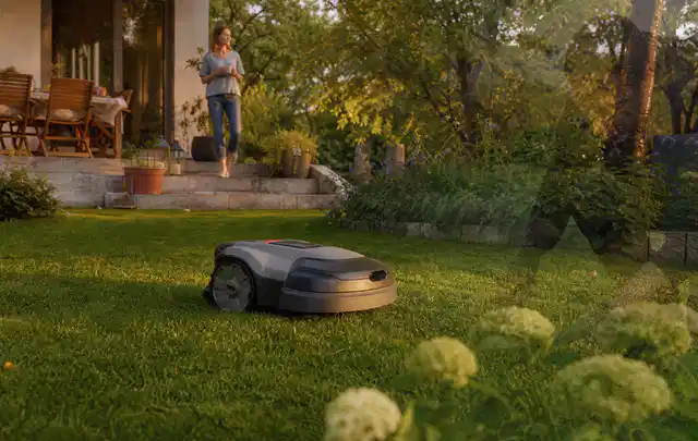Mähroboter fährt am Abend über einen Rasen im Familiengarten; Thema Mähroboter Garagen, Schwerpunkt Vergleich; Ergebnis.