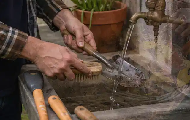 Hände reinigen gebrauchte Gartengeräte mit Bürste und Wasser am Außenbecken; Thema Mähroboter Installation, Schwerpunkt Checkliste; Ausgangslage.