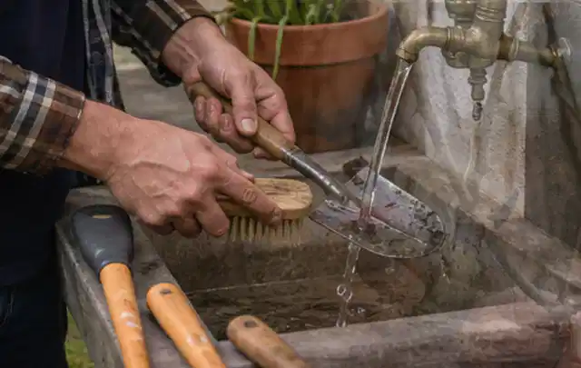 Hände reinigen gebrauchte Gartengeräte mit Bürste und Wasser am Außenbecken; Thema Mähroboter Messer, Schwerpunkt Bestenliste; Ergebnis.